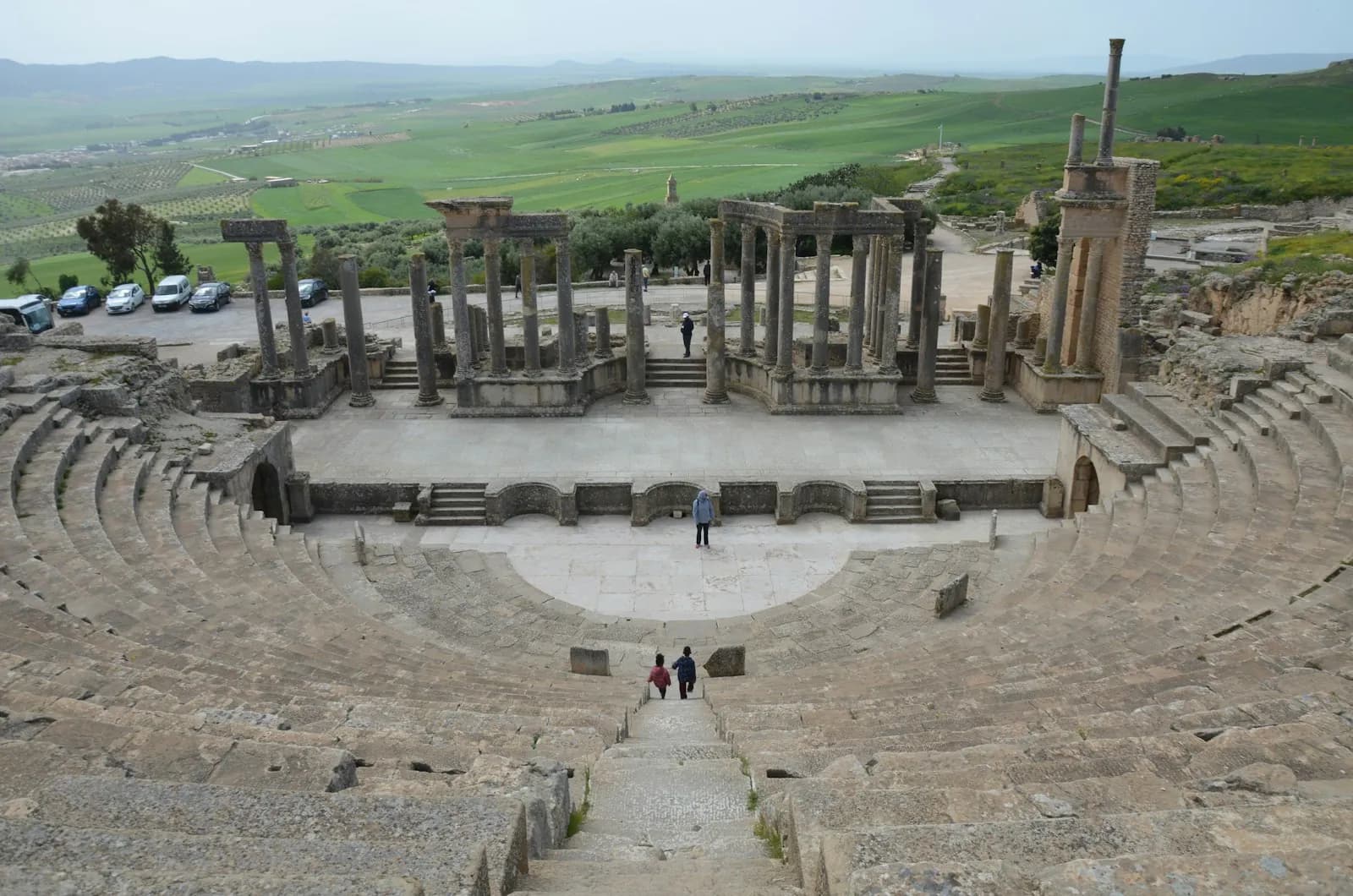 The Roman theatre of Dougga with green hills behind